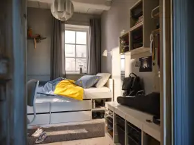 Ett mysigt tonårsrum kille med säng, skrivbord och förvaring. En gul filt och banankudde piggar upp.